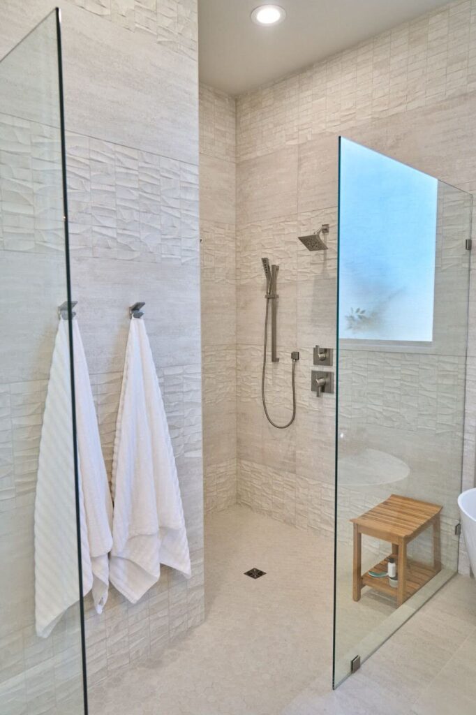 Master bathroom walk-in shower glass enclosure and natural light stone tile
