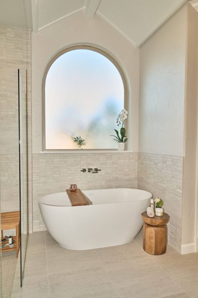 master bath soaker tub with arched window and spa theme