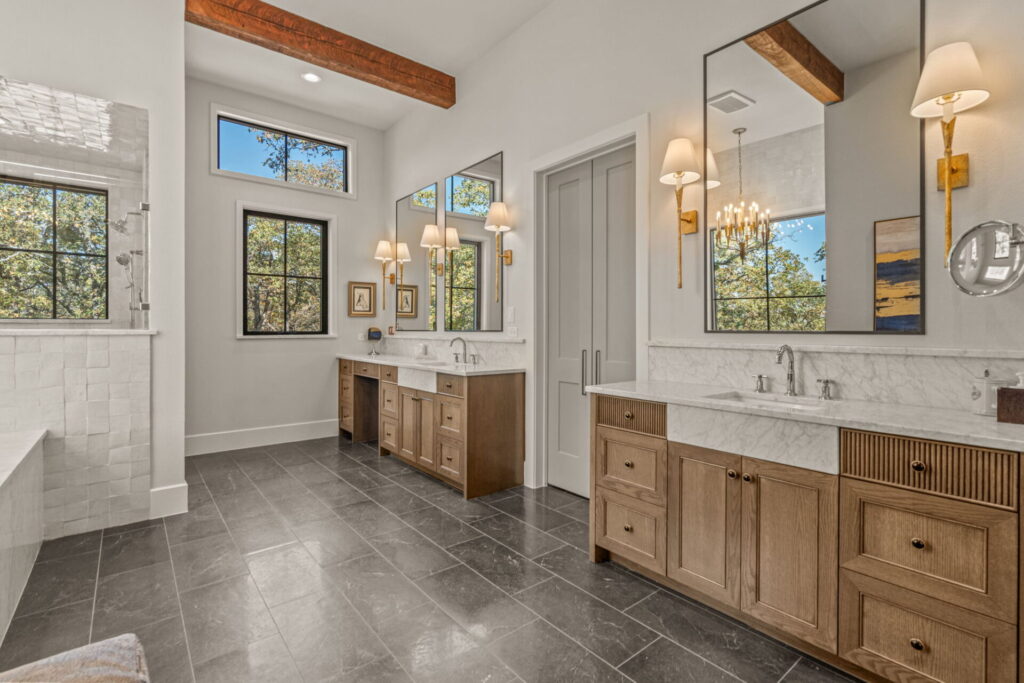 marble tub surround wood vanity dark floor chandelier beams tile pleated grey doors | The Design House